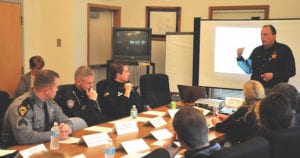     Bruce Langos, standing, chairman of the Montgomery County Drug Free Coalition and director of the Montgomery County Sheriff’s Office Criminal Intelligence Unit, and Jason Olson, seated third from left, addiction resource officer for the Dayton Police Department, presented information Friday afternoon about how Montgomery County officials deal with addiction, overdose deaths and crime caused by drug use at Consolidated Care Inc.’s West Liberty office. (EXAMINER PHOTO | REUBEN MEES)  Source: Montgomery Co. officials share strategies in fight against opiates